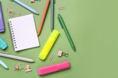 Yeşil zemin üzerinde okul kırtasiyesi olan boş bir defter