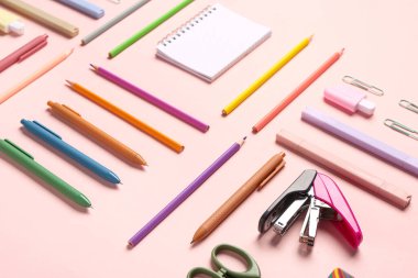 Pembe arka planda farklı kırtasiye malzemesi içeren defter.