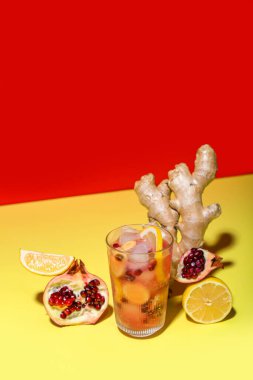 Bir bardak arkaplanda limon ve zencefil kökü olan lezzetli nar kokteyli.