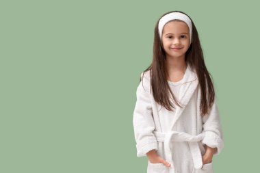 Yeşil arka planda bornozlu şirin küçük mutlu kız.