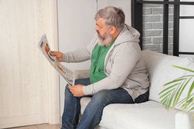 Evdeki kanepede oturan üzgün, yaşlı bir adamın portresi.