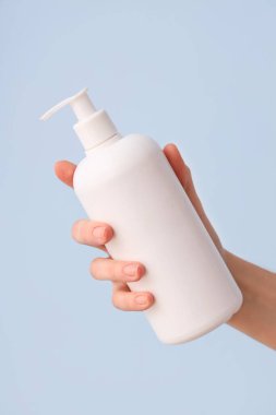 Arka planda doğal krem şişesi olan kadın eli, yakın plan.