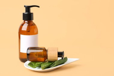 Doğal kozmetik ürünleri ve renk arka planında tabakta aloe vera olan şişeler.