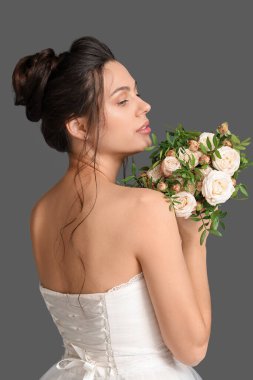 Gelinlik içinde güzel bir gelin ve arka planda bir buket var.