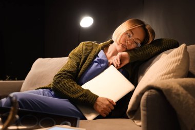 Diz üstü bilgisayarı olan kadın hemşire akşamları hastanede kanepede uyuyor.