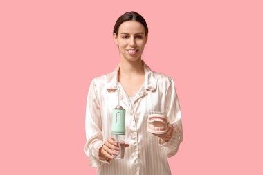 Pembe arka planda ağız sulandırıcısı ve çene modeli olan güzel genç bir kadın.