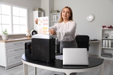 Kağıt öğütücüyle belgeleri yok eden yetişkin sekreter.