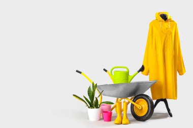 Yağmurluk, bitki, bahçe aletleri ve beyaz arka planda el arabası