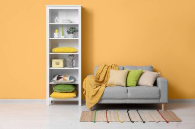 Oturma odasının iç tarafındaki turuncu duvarın yanında farklı dekoru ve rahat kanepesi olan beyaz askı.