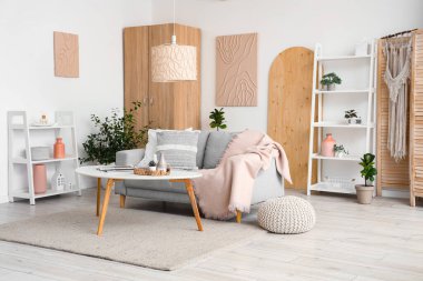 Koltuğu, çiçekleri, raf ünitesi ve sehpası olan şık bir oturma odası.