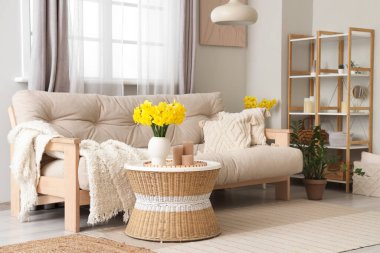 Rahat kanepesi, sehpası ve narsisli çiçekleri olan şık bir oturma odası.