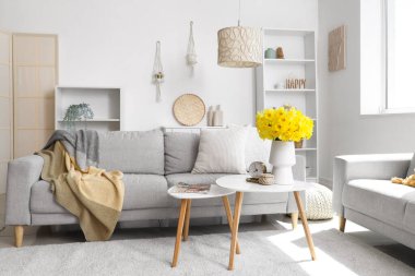 Rahat koltuklar, raf ünitesi ve vazo hafif oturma odasında narsisli çiçekler.