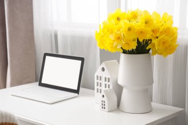 Şık bir odada dizüstü bilgisayarı ve vazosu olan bir iş yeri.