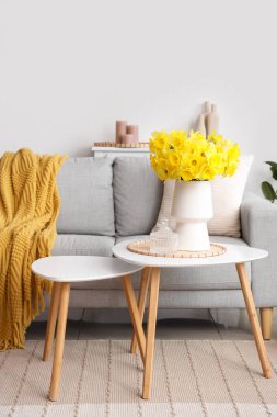 Güzel bir oturma odası, rahat bir kanepe, narsisli çiçekler ve kahve masaları.