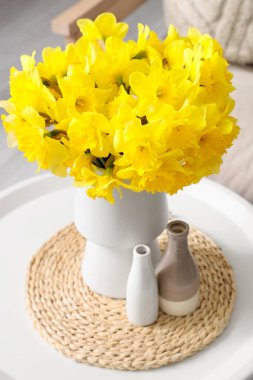 Oturma odasında vazo dolusu narsisli kahve masası.