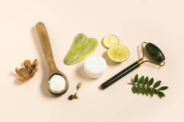 Yüz masajı silindiri, guasha ve hafif arka planda kozmetik maske için doğal malzemeler