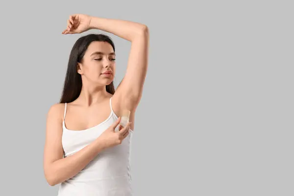 stock image Beautiful young woman using crystal deodorant on white background