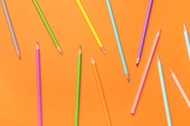 Turuncu arka planda renkli kalemler grubu