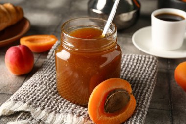 Kayısı reçelli kavanoz ve gri fayansta bir fincan kahve.