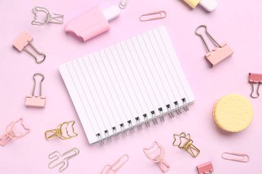 Pembe arka planda farklı kırtasiye malzemesi içeren defter.