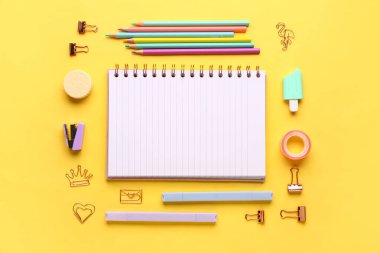 Sarı arka planda farklı kırtasiye malzemesi içeren defter