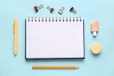 Mavi arkaplanda farklı kırtasiye malzemesi olan defter