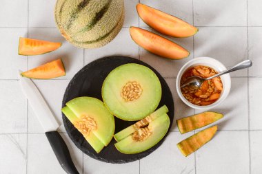 Beyaz karo zemin üzerinde lezzetli olgun kavunlarla kayrak tahtası