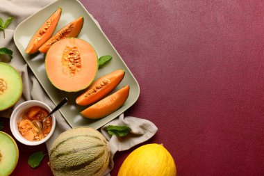 Kırmızı arka planda lezzetli olgun kavunlu tabak.