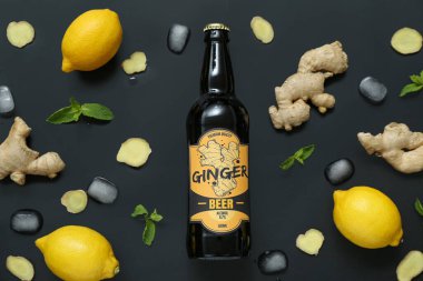 Siyah zemin üzerinde taze zencefilli bira, nane, limon ve buz küpleriyle kompozisyon