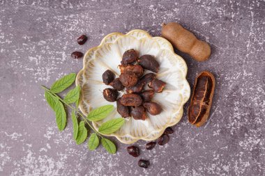 Gri arka planda lezzetli tamarinler, tohumlar ve yapraklar