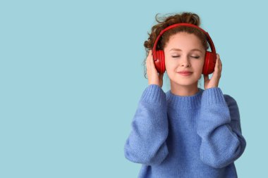 Mavi arka planda müzik dinleyen rahat genç bir kadının portresi