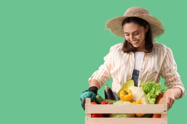 Yeşil arka planda bir kutu taze sebzeli kadın çiftçi.