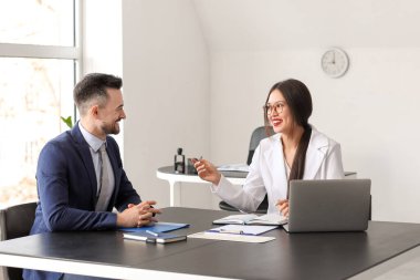 Human resources manager interviewing male applicant at table in office