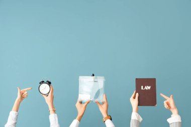 Hands holding ballot box, book of law and alarm clock on blue background. Election concept