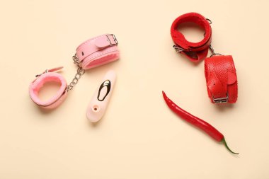 Farklı kelepçeler, elektrikli süpürge ve bej arka planda kırmızı biber.