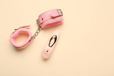 Süpürge vibratörü ve bej arka planda pembe kelepçeler.