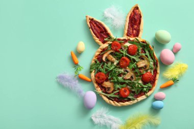 Turkuaz arka planda Paskalya kutlaması için lezzetli pizza ve yumurta boyalı kompozisyon