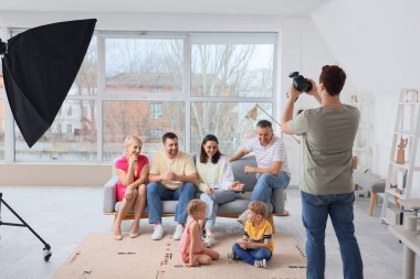 Stüdyoda küçük çocuklu aile fotoğrafı çeken erkek fotoğrafçı.