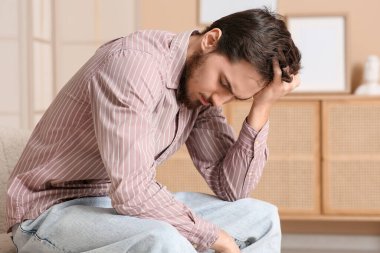 Evdeki kanepede yorgun genç bir adam.