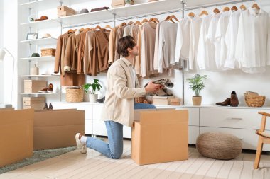 Soyunma odasında kostüm kutuları ve şık giysileri olan yakışıklı bir genç.