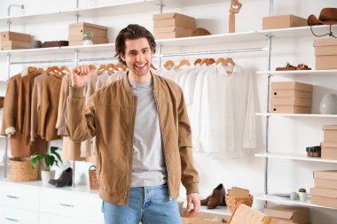 Soyunma odasında kostüm kutuları ve şık giysileri olan yakışıklı genç adam.