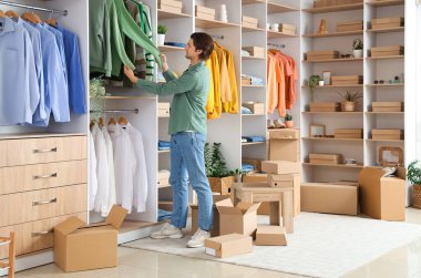 Yakışıklı genç adam giyinme odasında şık kıyafetler düzenliyor.