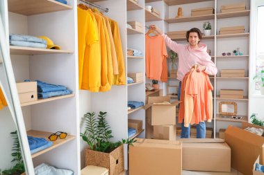 Soyunma odasında şık kıyafetler ayarlayan yakışıklı genç adam.