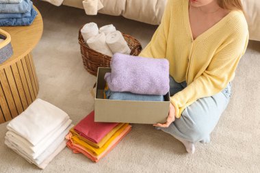 Yerde otururken elinde temiz giysiler tutan bir kadın.