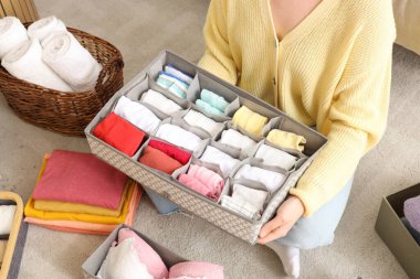 Yerde otururken elinde temiz giysiler tutan bir kadın.