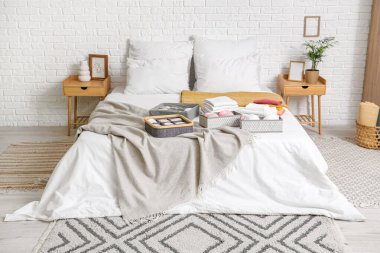 Aydınlık yatak odasında temiz giysileri olan organizatörler.