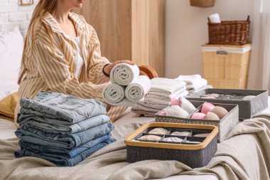 Farklı temiz elbiseli bir kadın yatakta oturuyor.