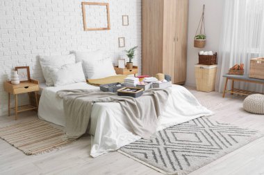 Aydınlık yatak odasında temiz giysileri olan organizatörler.