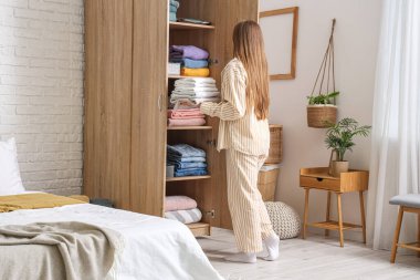 Genç bir kadın, temiz giysileri dolaba katlıyor.