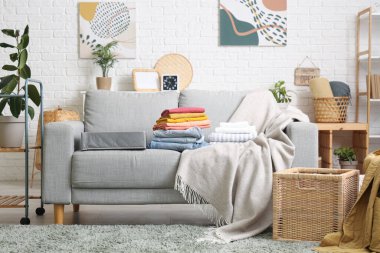 Kanepenin üzerinde temiz giysiler olan modern oturma odasının şık bir iç mekanı.